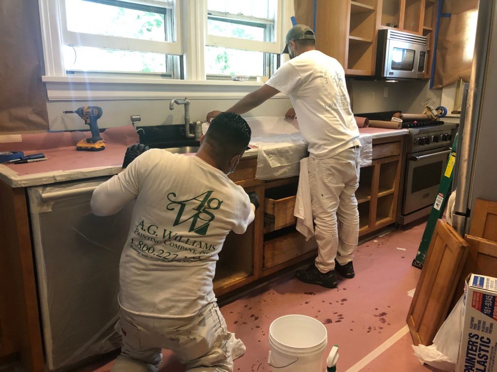 men working in kitchen repainting wood cabinets