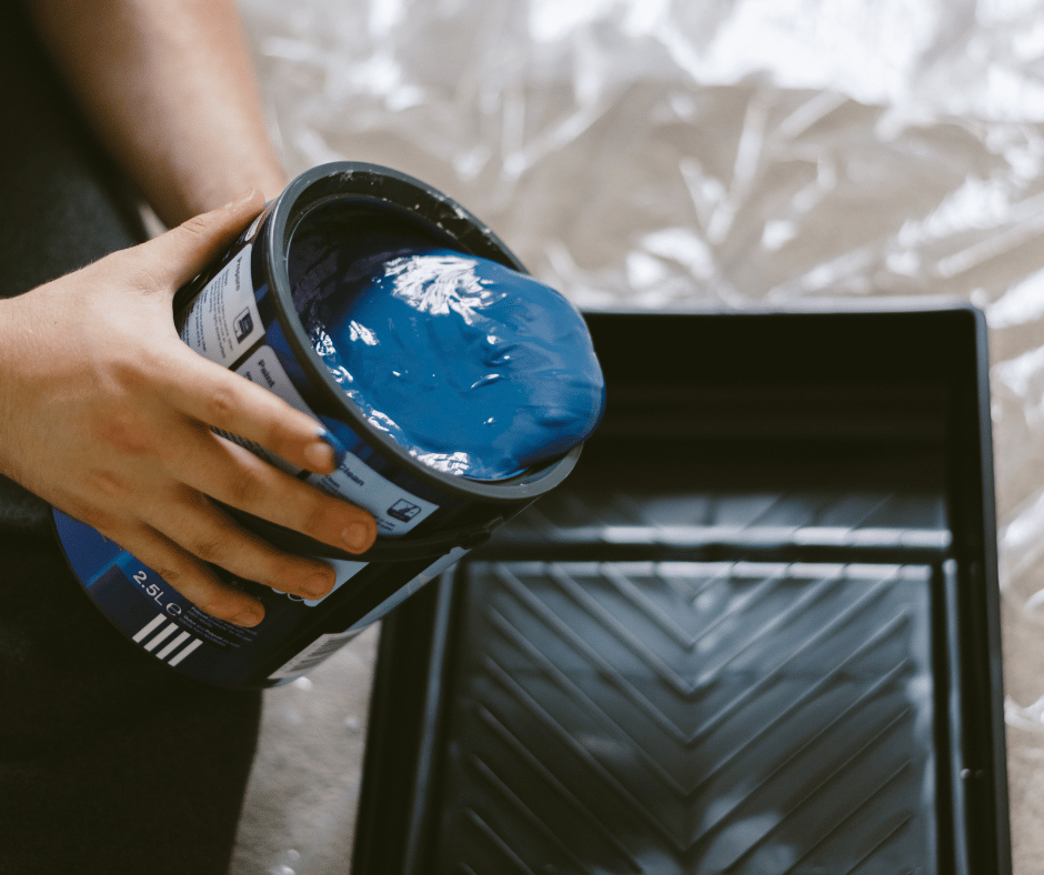 blue paint being poured into black paint tray